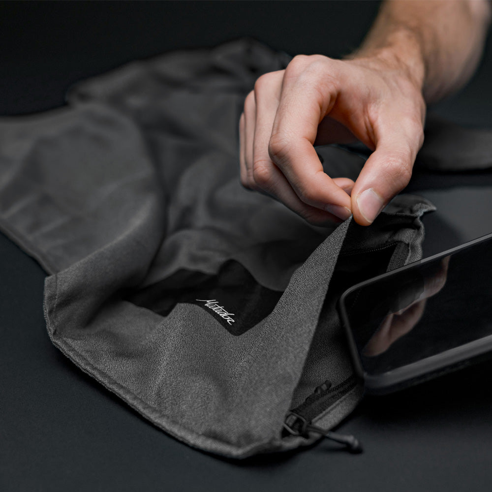 close up studio photo of cell phone being placed in charcoal beach towel pocket