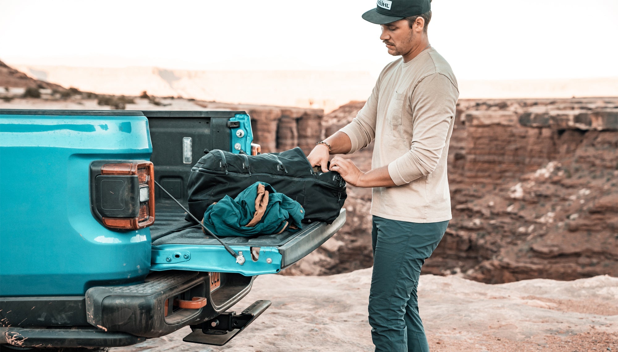 Man packing SEG45 in truck bed at the edge of a desert canyon