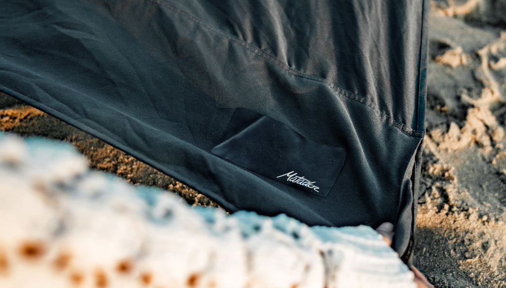 close up view of matador patch on pocket corner of beach towel being laid on beach