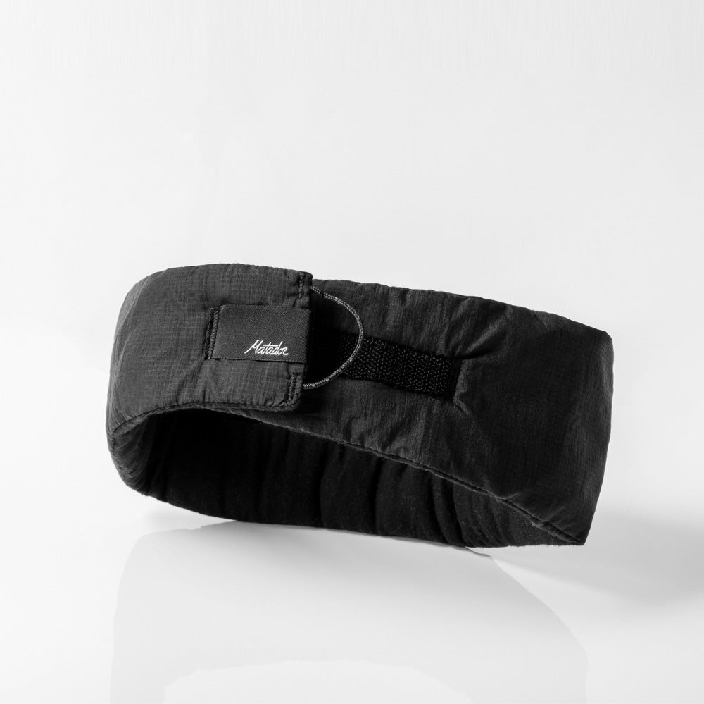 back view of circular black eye mask sitting on reflective light gray background