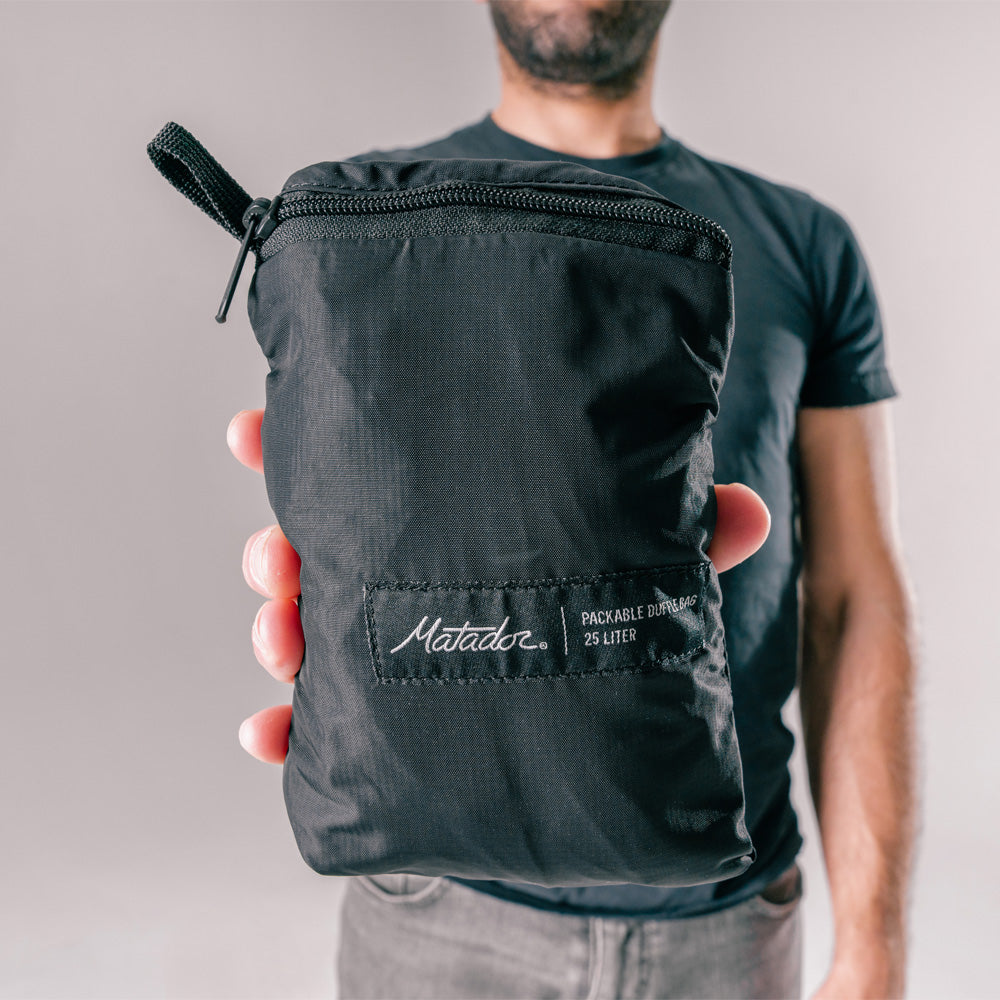 man holding close up view of packed up black duffle