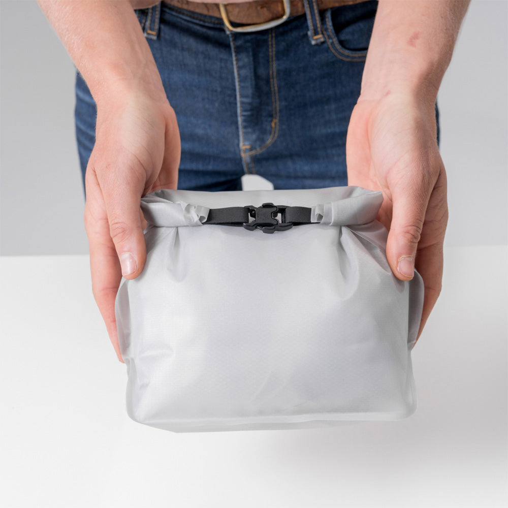 hands holding closed white toiletry case straight to camera