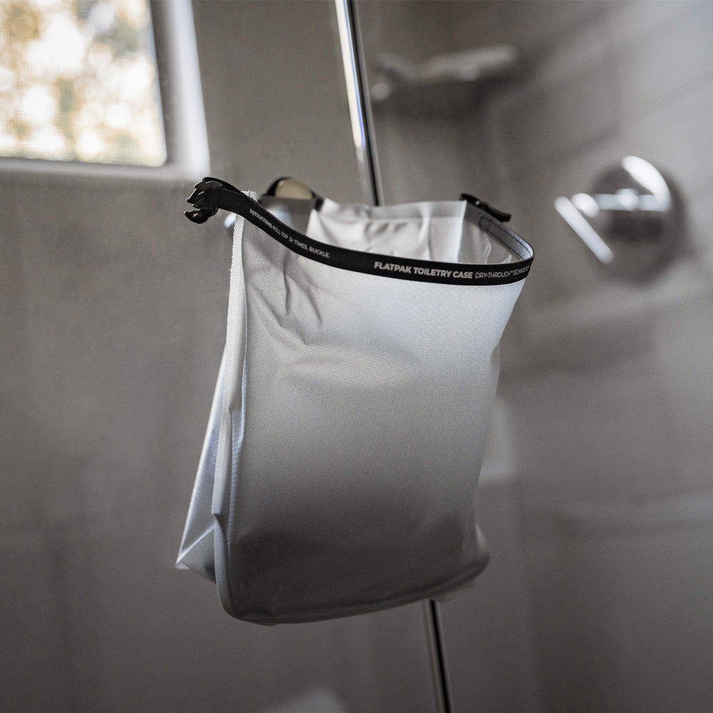 white toiletry case hanging open on shower door