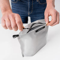 hands zipping white toiletry case open