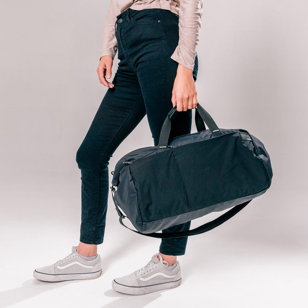 woman holding black duffle by the straps at her side