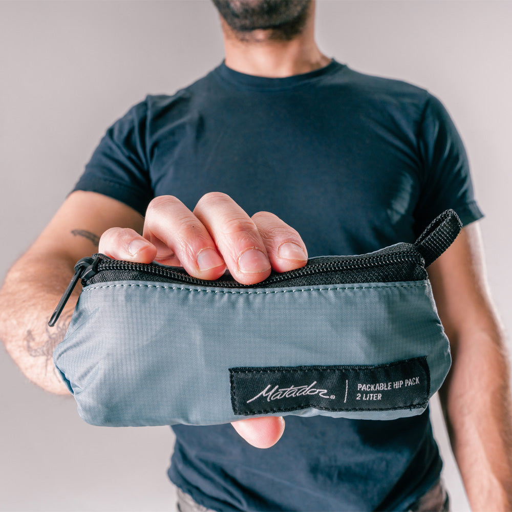 man holding close up view of packed up slate blue sling bag