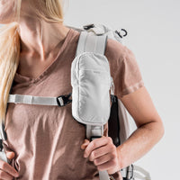 woman wearing white speed stash on her white backpack strap