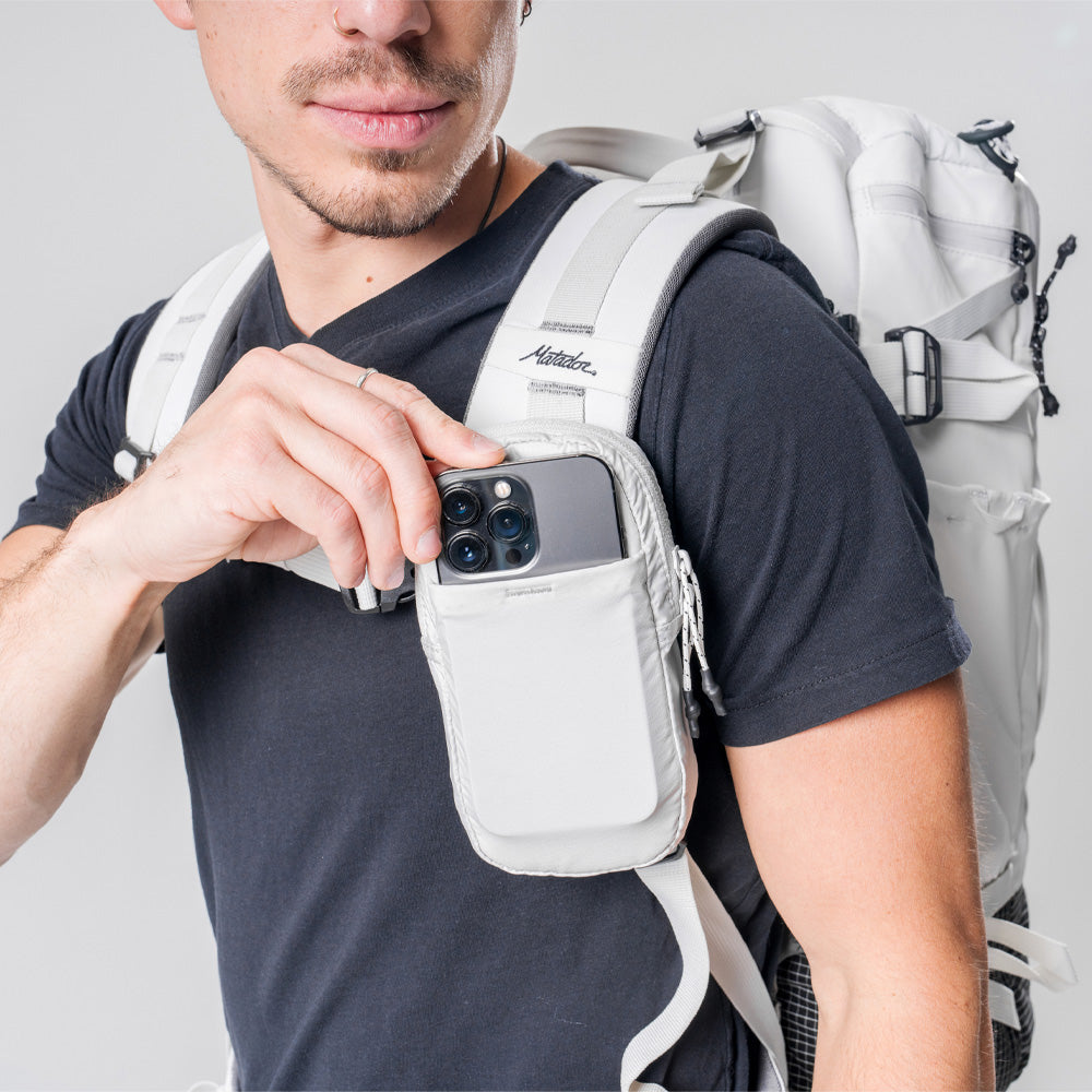 man pushing cellphone into white speed stash front pocket