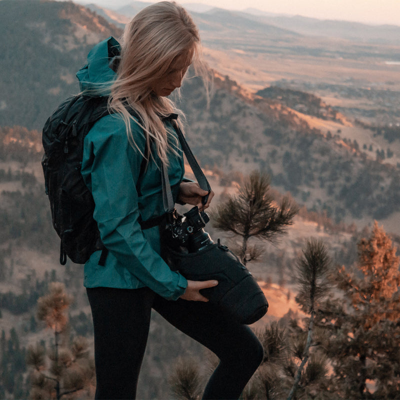 Woman on mountain, pulling camera out of base layer