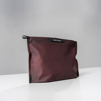 3/4 view of garnet zipper toiletry case on light gray background