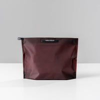 back view of garnet zipper toiletry case on light gray background