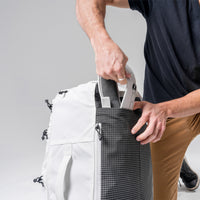 man stowing White SEG45 shoulder straps in back of pack