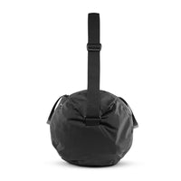 side view of black duffle on white background