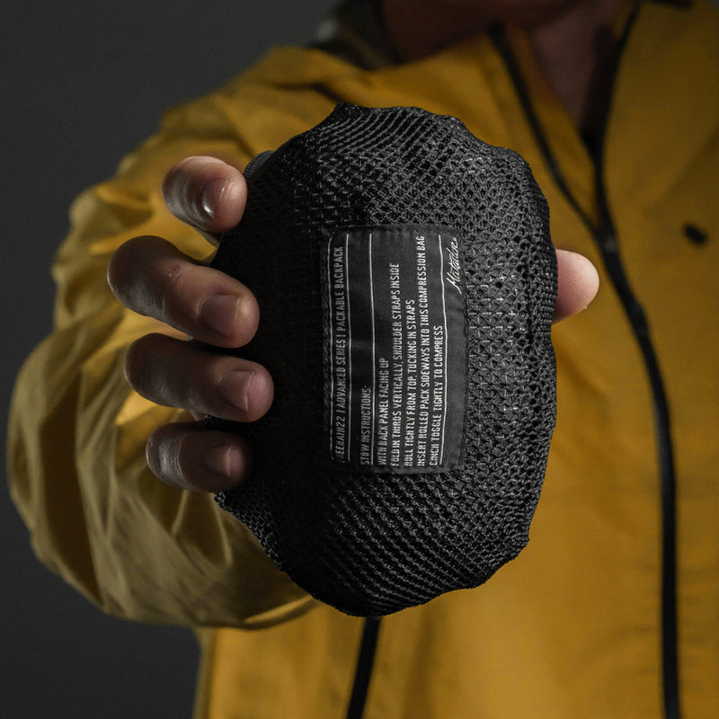 Man holding packed down backpack pouch