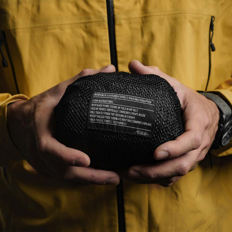 Man holding packed down backpack pouch