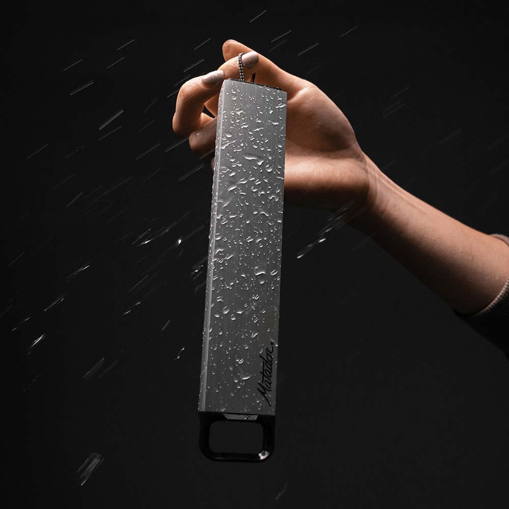 Hand holding pill canister covered in beaded water on black background