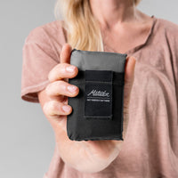 Woman holding black Pocket Blanket straight at camera