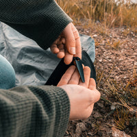 Close up view of woman holding built in stake on rocky terrain