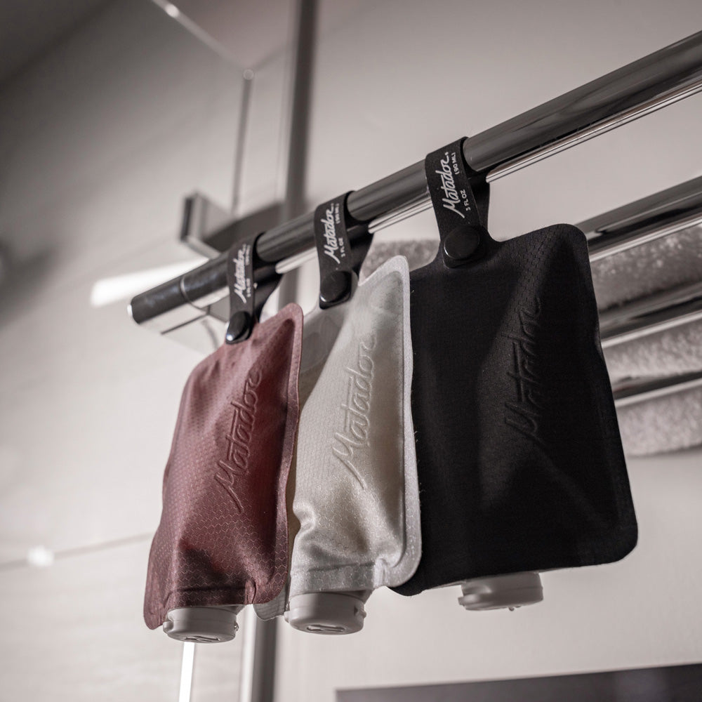 3 toiletry bottles hanging from towel rack in bathroom