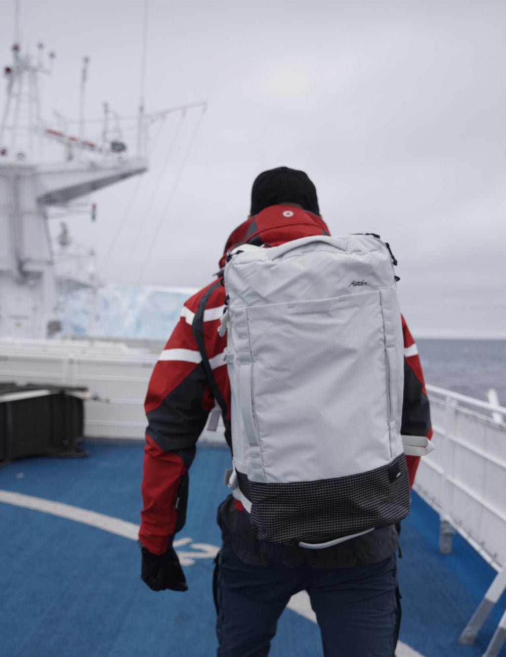 Man on an Antarctic ship, wearing red jacket and white GlobeRider 45 Travel Pack