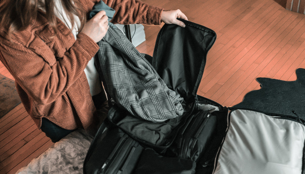 woman removing shirt from black packing cube in cozy warm setting