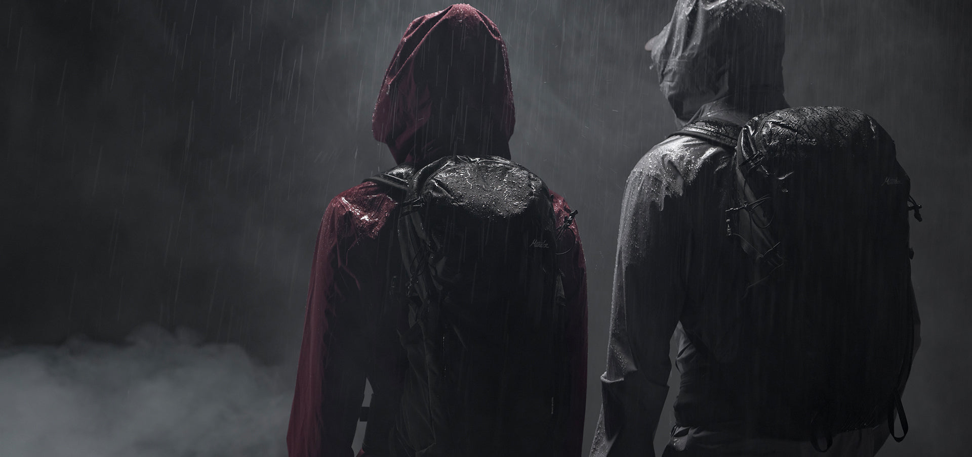 Back view of two people in rainy, foggy setting, wearing Beast backpacks