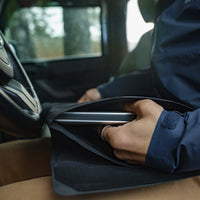 Man in car, pulling laptop from base layer