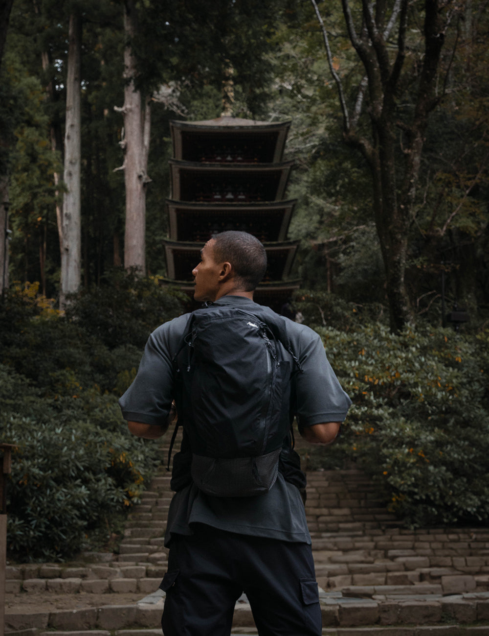 Man wearing black backpack, standing in Japanese garden