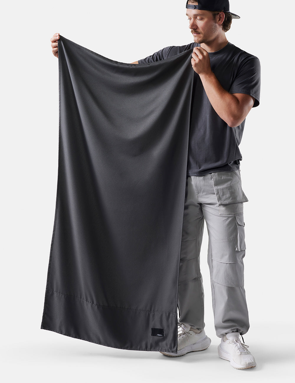 man on white background holding up grey towel