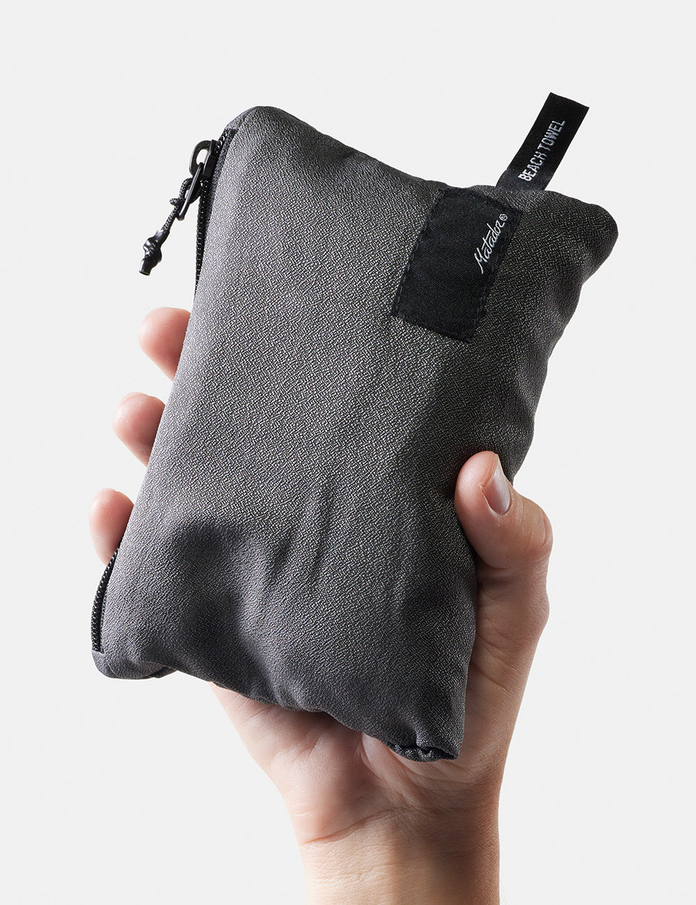 hand on white background holding up packed up beach towel