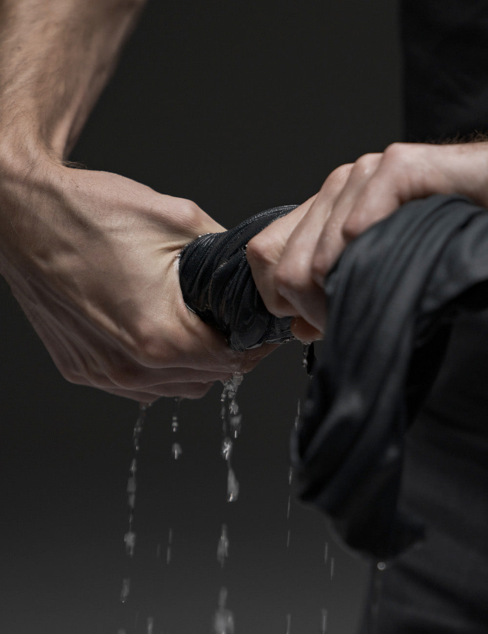 hands wringing out water from gray towel