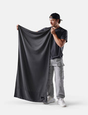 Man holding a large gray fabric against a white background