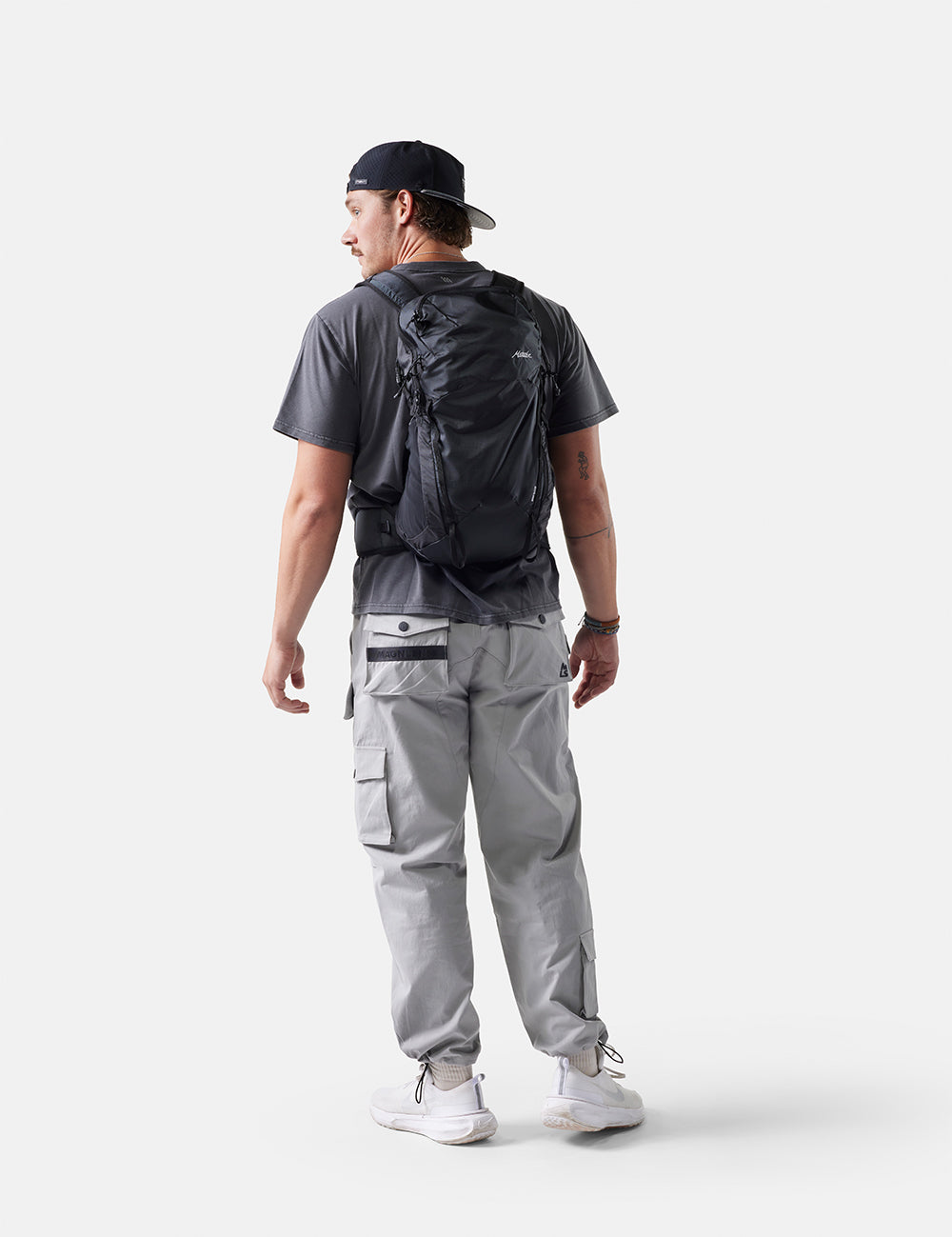 Person wearing a black backpack and gray pants on a white background