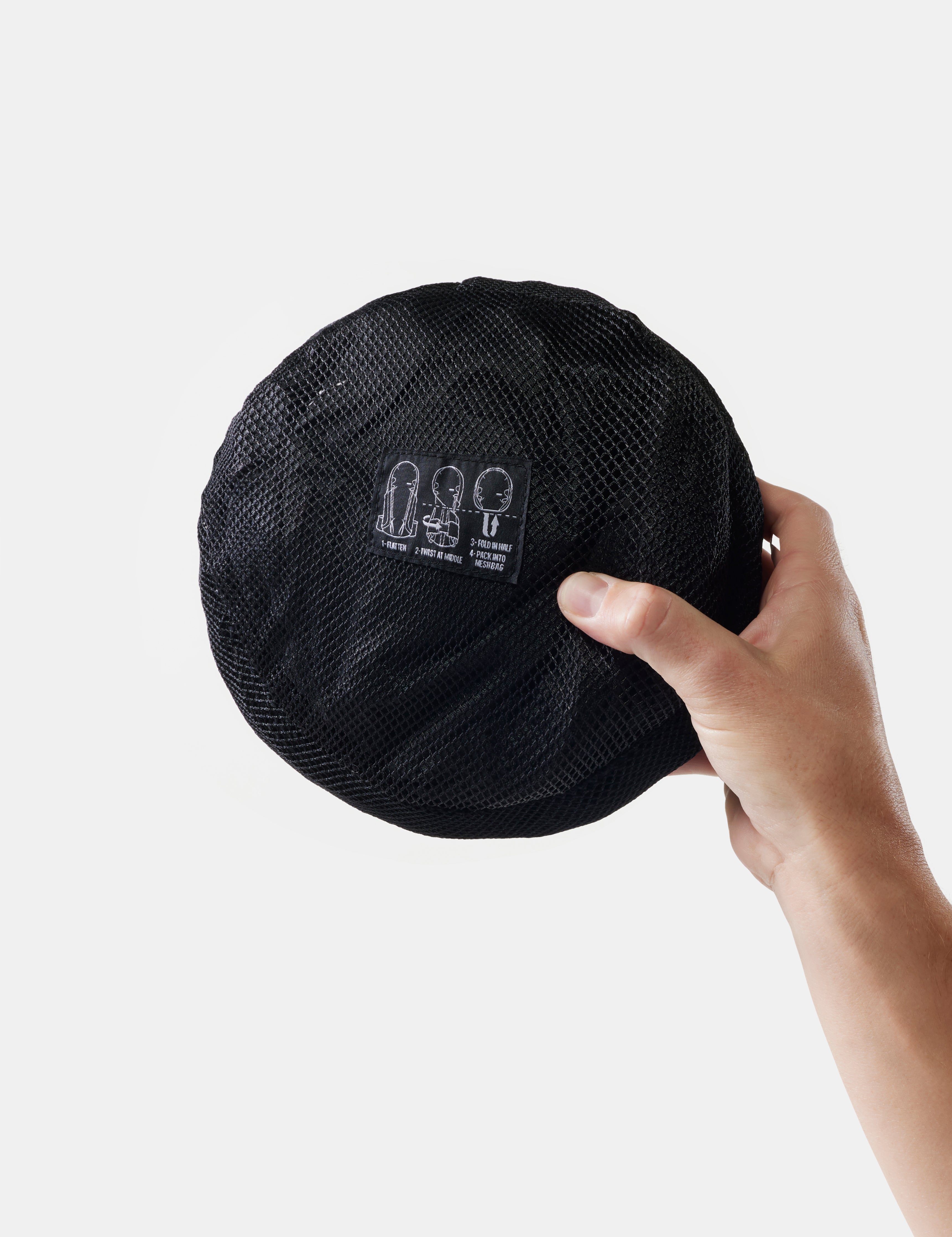 Black packed up bag held by a hand against a light gray background