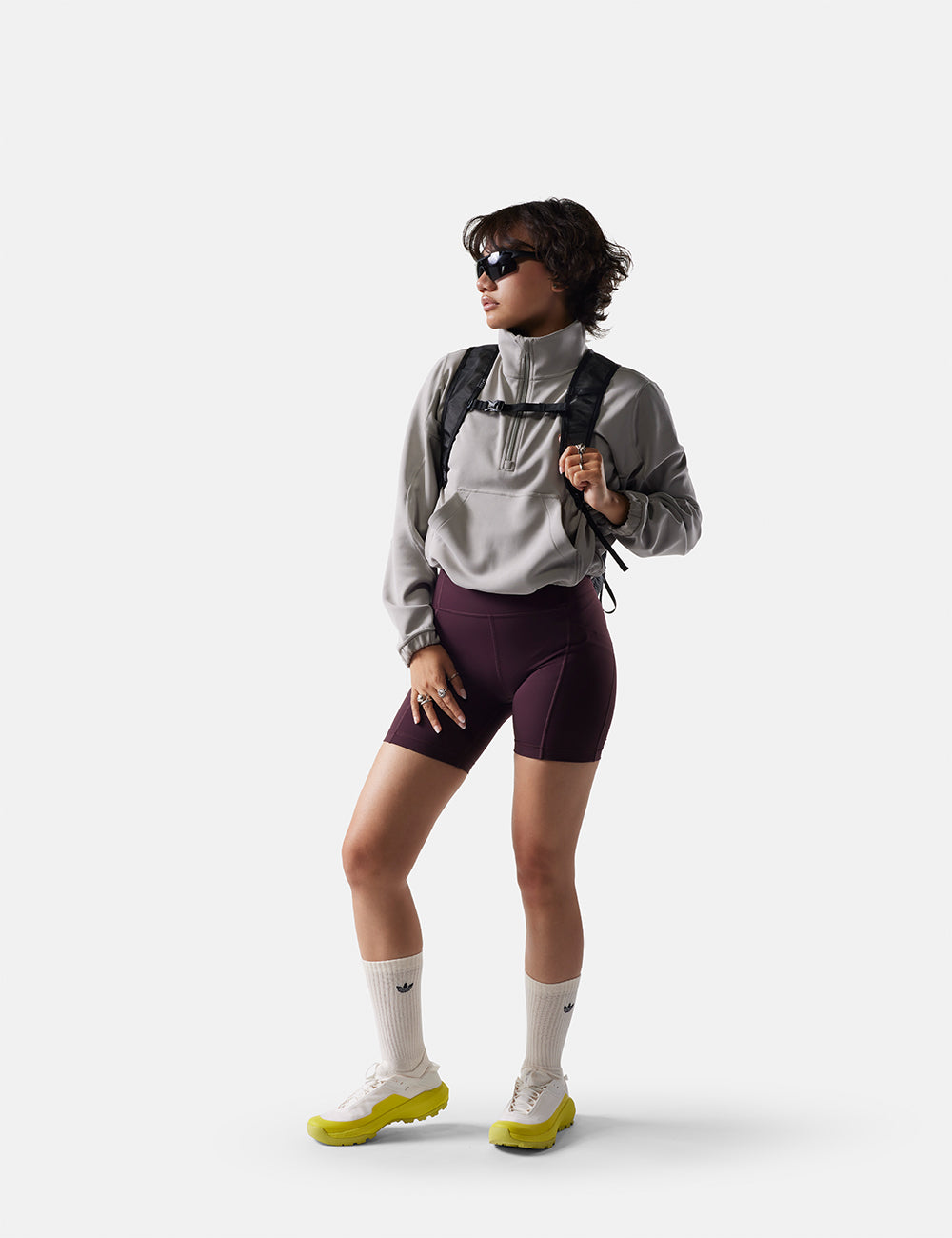 Person wearing a gray jacket, maroon shorts, and white shoes on a white background