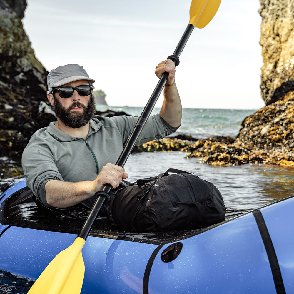 Man in sea kayak with black duffle on his lap