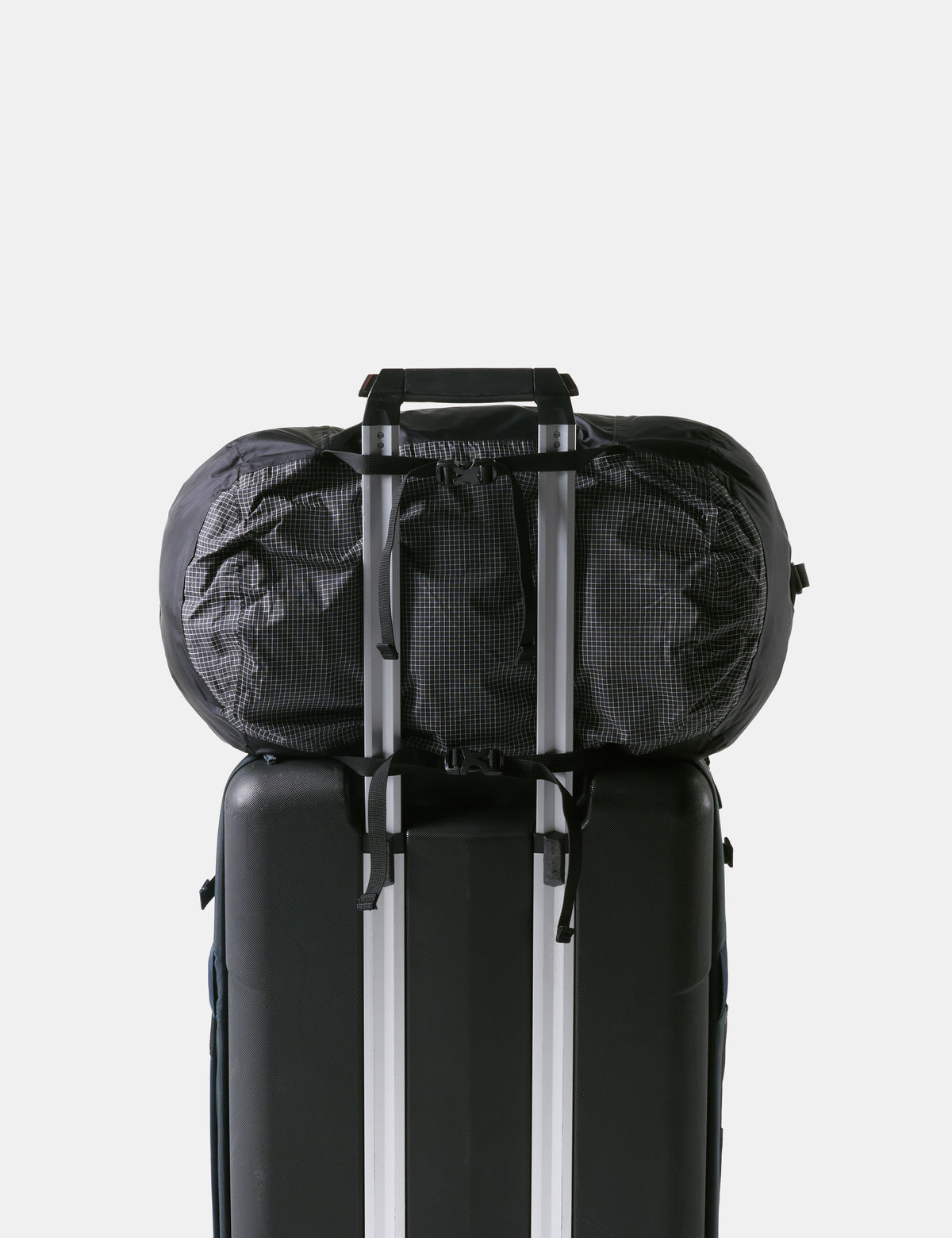 Black travel backpack with a clear front compartment attached to a suitcase on a light gray background