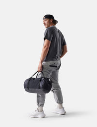 Man holding a black duffel bag against a white background