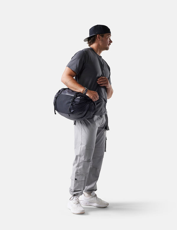 Person holding a duffel bag against a white background