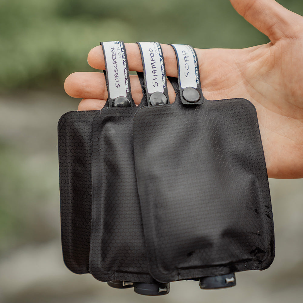 hand holding 3 toiletry bottle by loops with text &quot;sunscreen, shampoo, soap&quot;