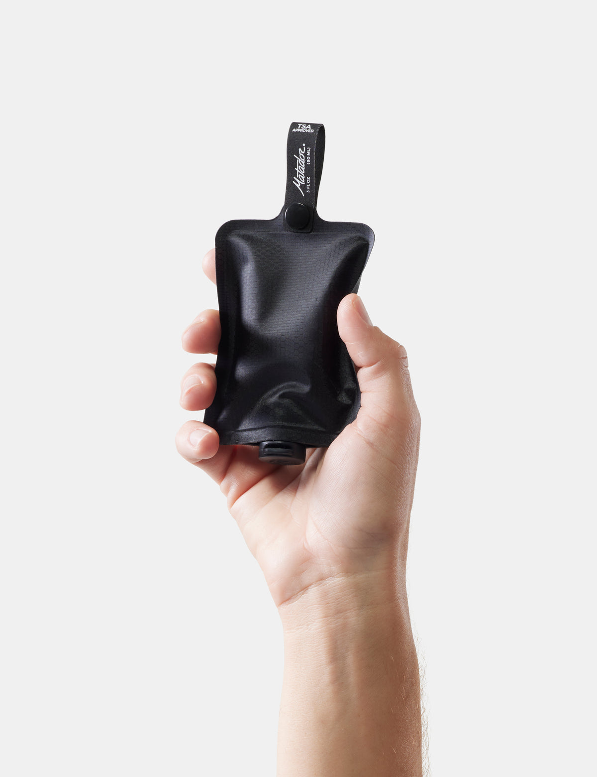 Hand holding toiletry bottle against a white background