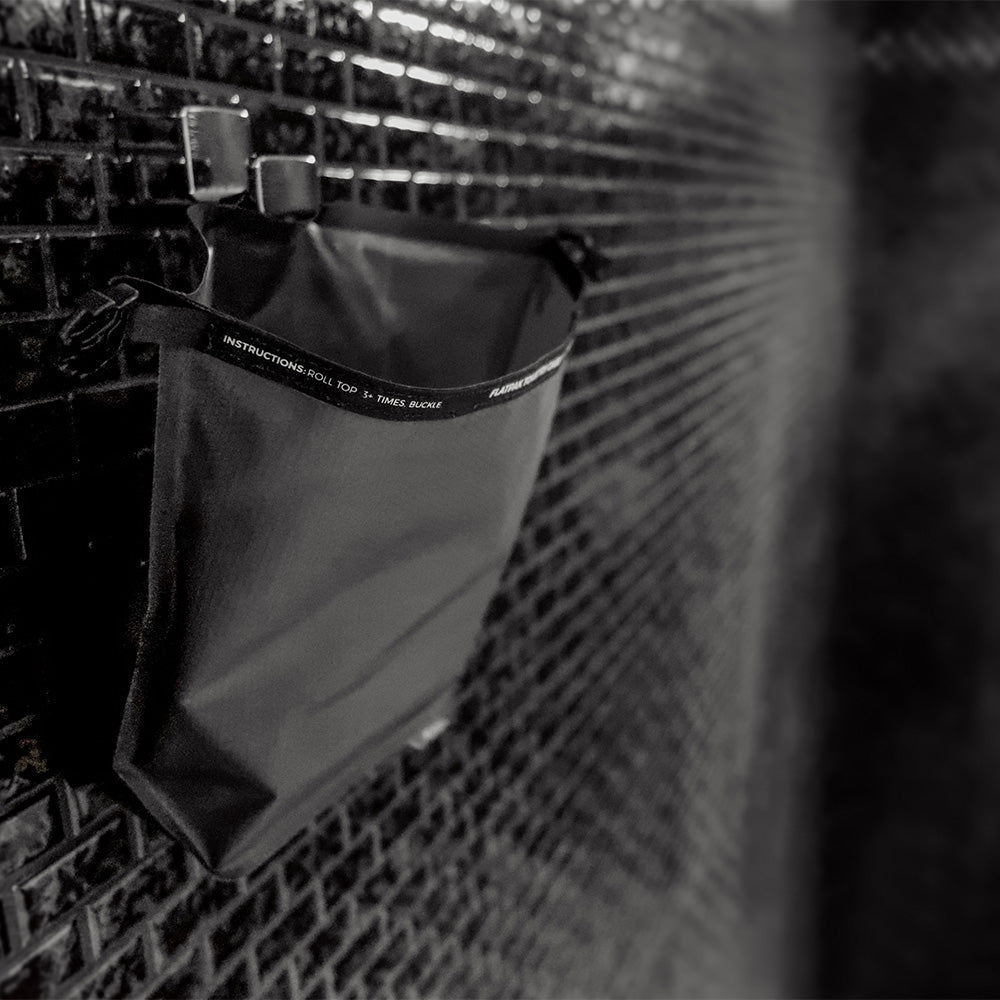 Black toiletry case hanging on black tile wall