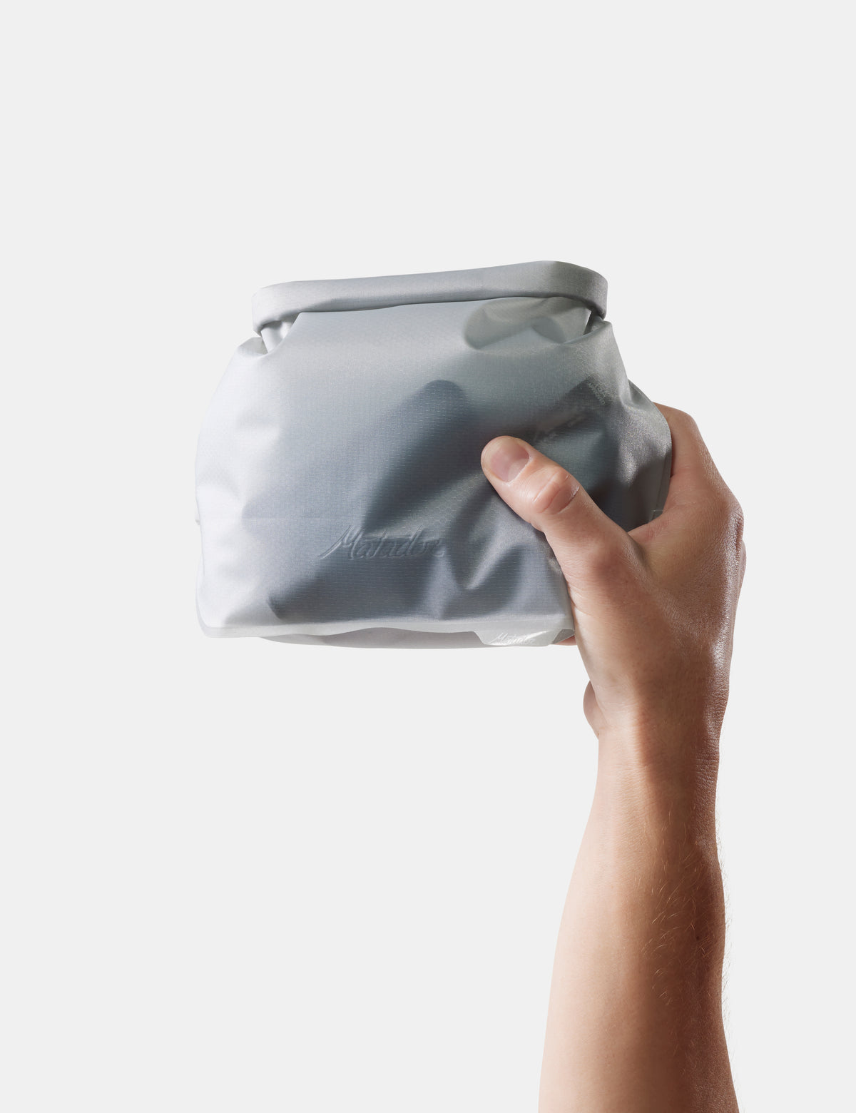 Hand holding white toiletry case against a white background