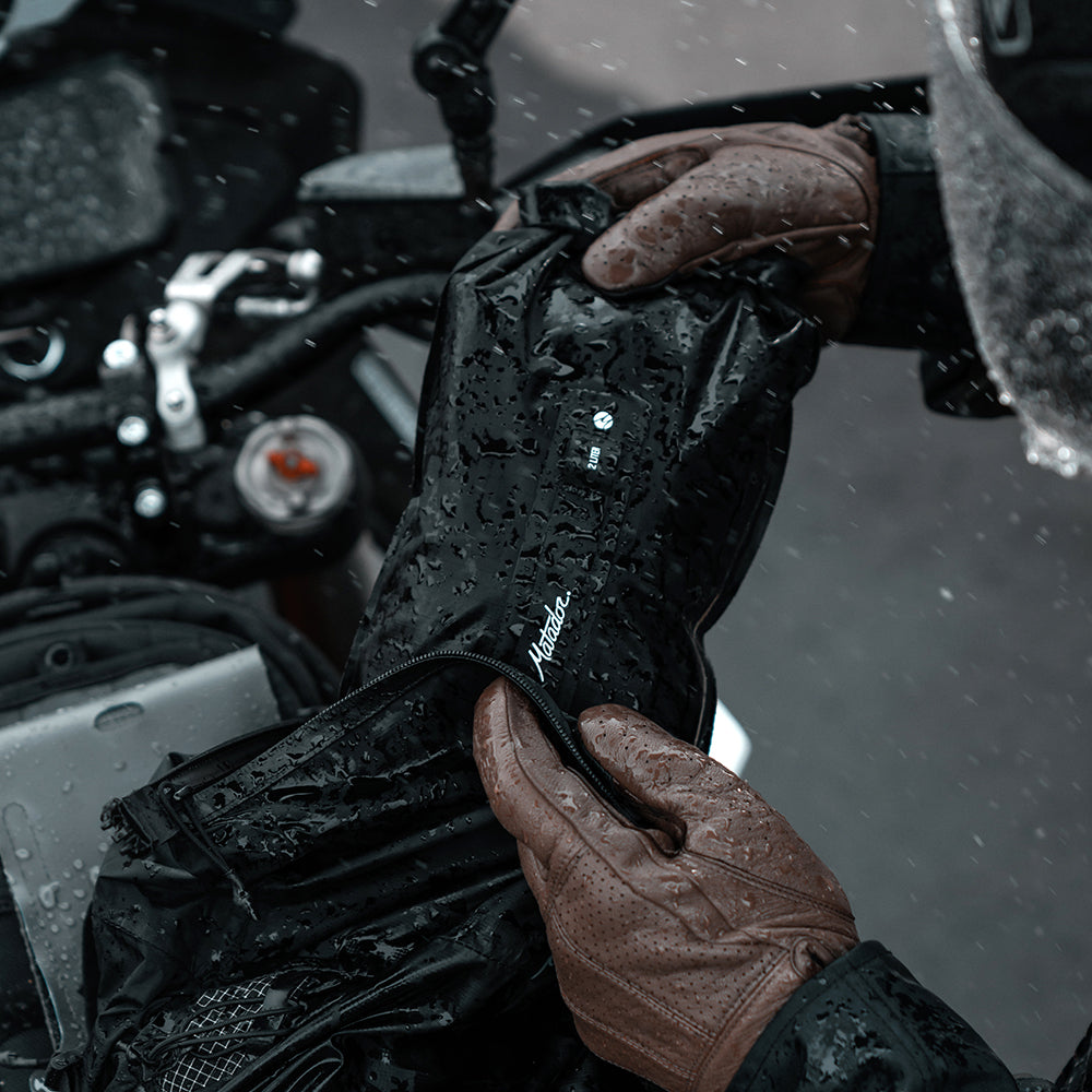 motorcyclist putting dry bag in their pack in pouring rain