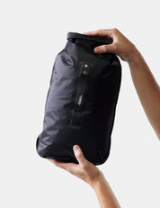 Black dry bag held by a person against a white background