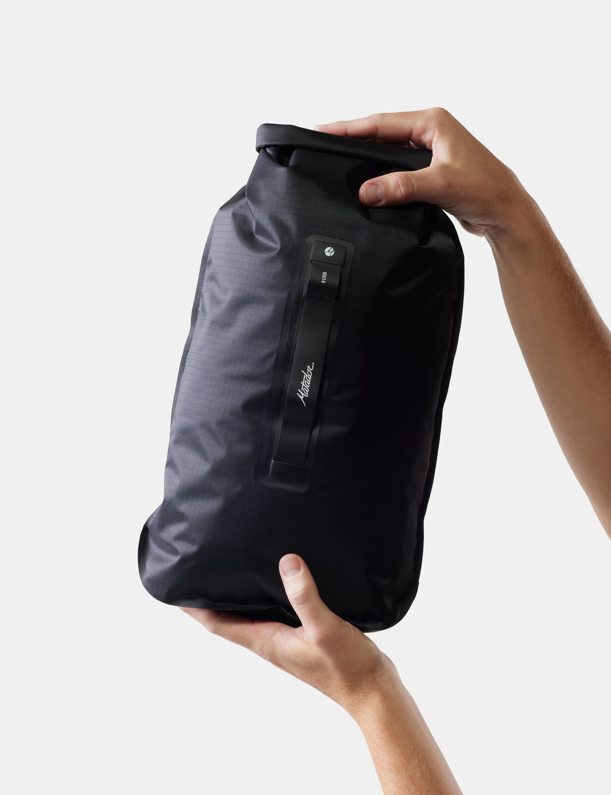 Black dry bag held by a person against a white background