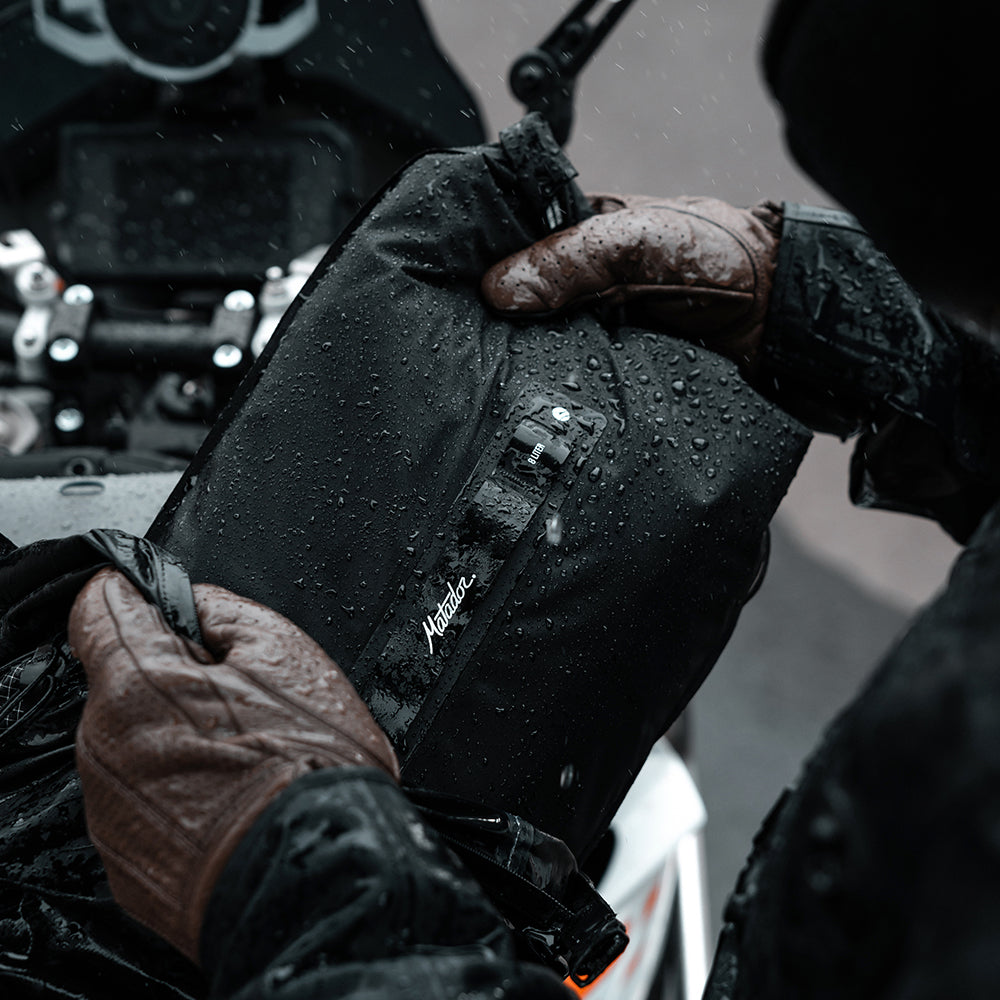 motorcyclist putting dry bag in their pack in pouring rain