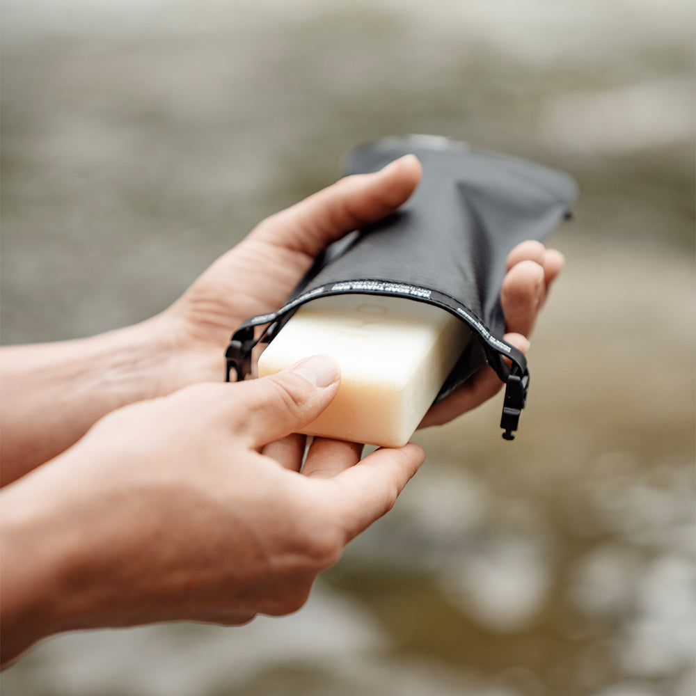 pulling soap out of soap bar case next to a river