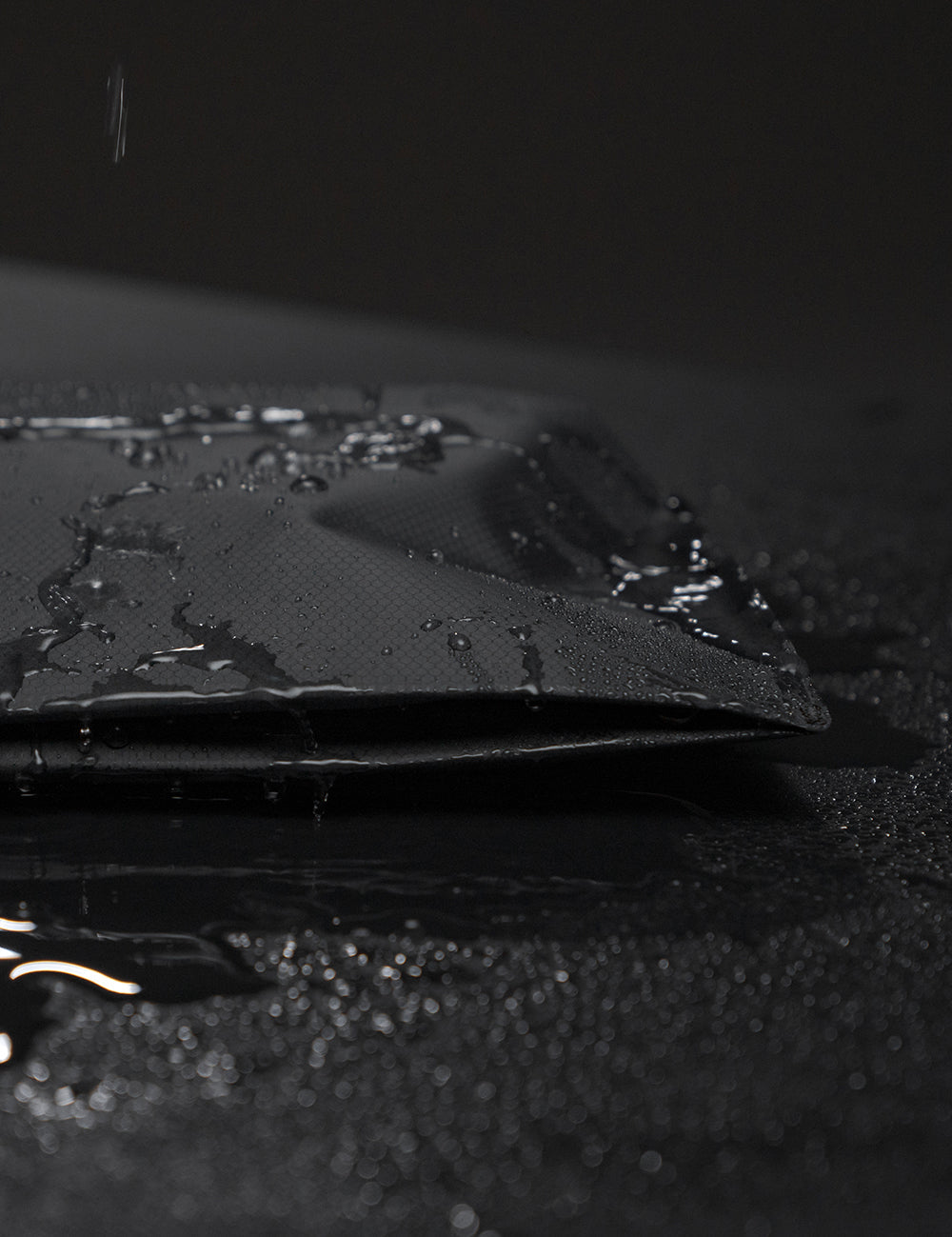 toiletry case on black background covered in beaded water