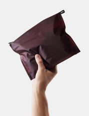 hand holding garnet toiletry case on white background